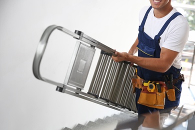 Professional builder carrying metal ladder up stairs, closeup