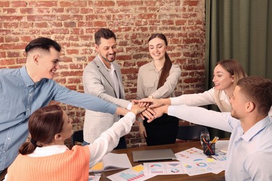 Office employees joining hands during meeting at work