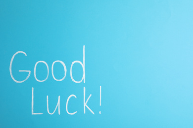Phrase GOOD LUCK on light blue background, top view. Space for text