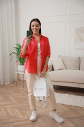 Photo of Young woman taking mirror selfie in stylish outfit at home. Morning routine