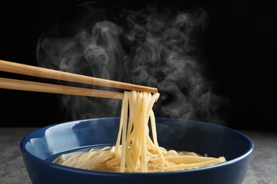 Image of Eating noodle dish with chopsticks against black background
