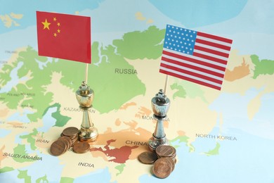 Photo of Chess pieces with American and Chinese flags and coins on map. Trade war