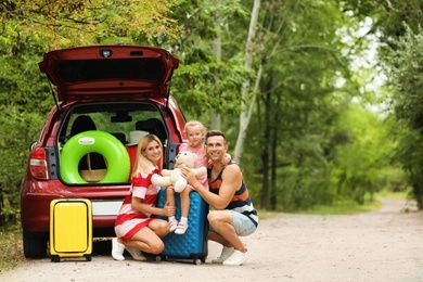 Happy family near car trunk with suitcases outdoors. Space for text