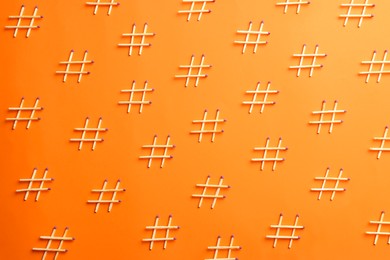 Photo of Hashtag symbols made of wooden matches on orange background, flat lay