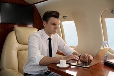 Businessman working on laptop at table in airplane during flight