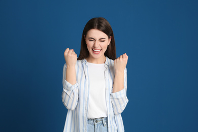 Portrait of excited young woman on blue background