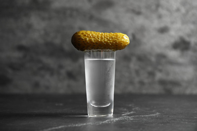 Cold Russian vodka with pickle on black table