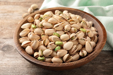 Organic pistachio nuts in bowl on wooden table