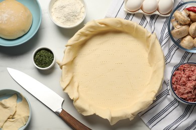 Photo of Flat lay composition with raw dough and ingredients on white table. Baking meat pie