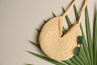 Elegant woman's straw bag with tropical leaf and sunglasses on beige background, top view. Space for text