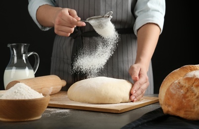 Photo of Female baker preparing bread dough at kitchen table