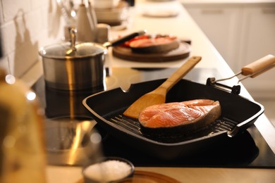 Frying pan with fresh salmon steak on cooktop