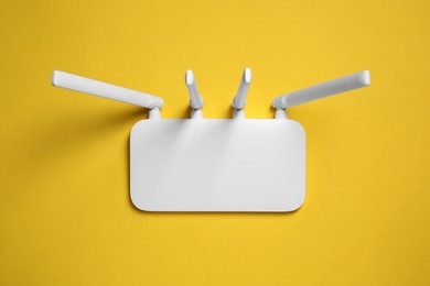 Photo of New white Wi-Fi router on yellow background, top view