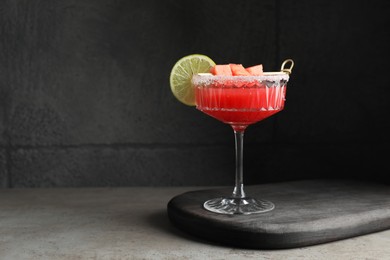 Cocktail glass of delicious fresh watermelon juice with lime on grey table. Space for text