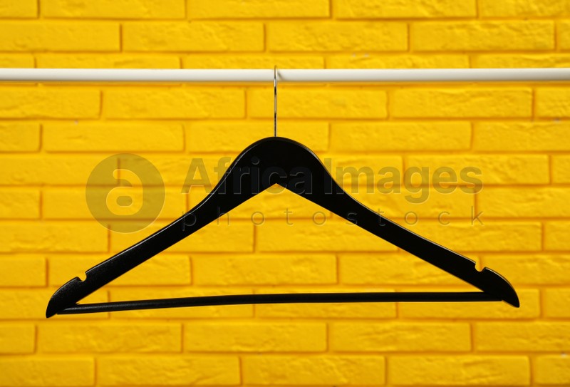 Wardrobe rack with black hanger near yellow brick wall
