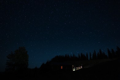 Beautiful view of house near dark forest under starry sky at night