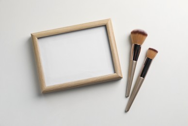 Blank board with makeup brushes on white background, flat lay. Space for text