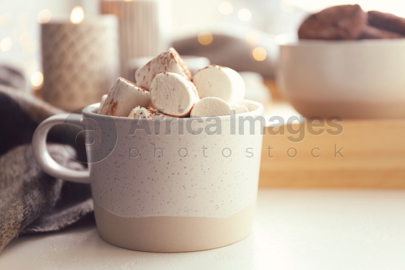 Cup of delicious hot cocoa with marshmallows on white table, closeup. Winter drink