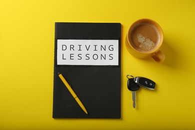 Flat lay composition with workbook for driving lessons on yellow background. Passing license exam