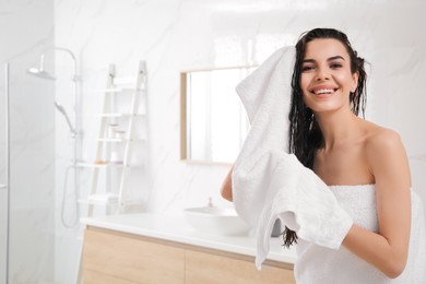 Happy young woman drying hair with towel after washing in bathroom. Space for text