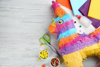 Photo of Flat lay composition with cardboard donkey and materials on white wooden table, space for text. Pinata DIY