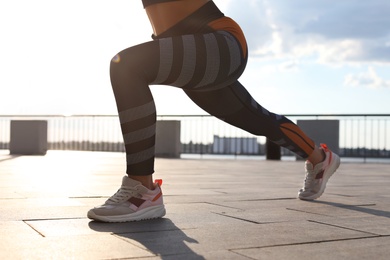 Young woman doing exercise outdoors in morning, closeup