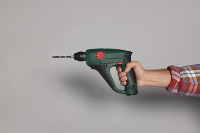Man with power drill on grey background, closeup