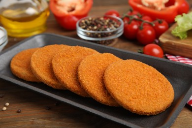 Uncooked breaded cutlets on wooden table. Freshly frozen semi-finished product