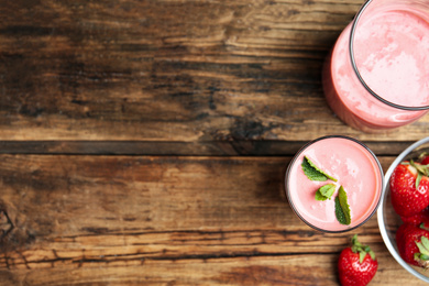 Tasty strawberry smoothies in glasses on wooden table, flat lay. Space for text