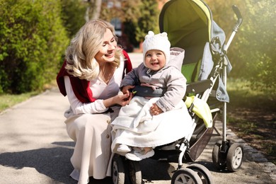 Happy mother with her daughter in stroller outdoors on sunny day