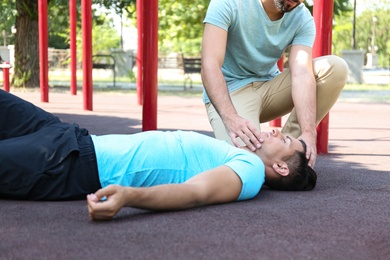 Passerby giving first aid to unconscious man outdoors