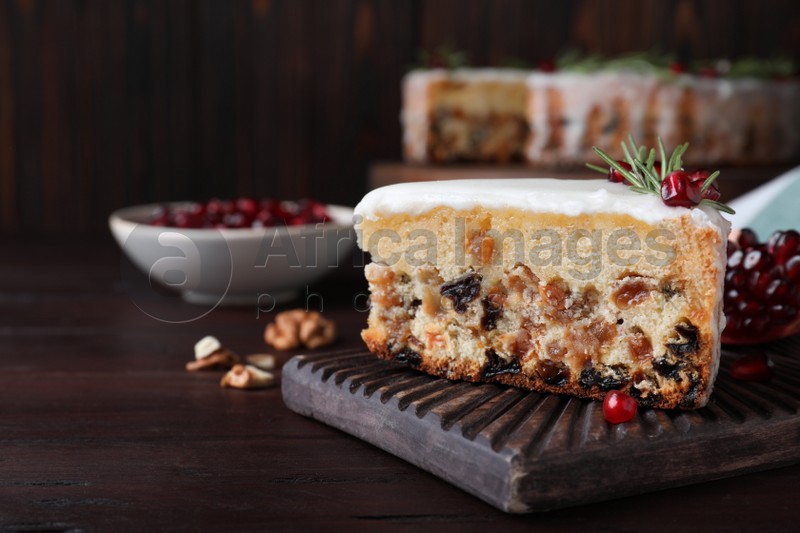 Photo of Piece of traditional homemade Christmas cake and fresh pomegranate on wooden table, closeup. Space for text