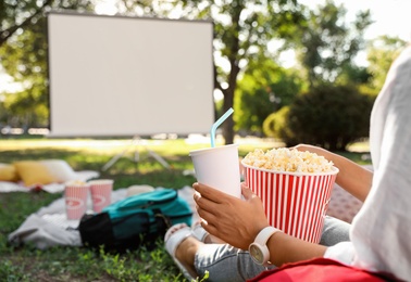 Woman with popcorn watching movie in open air cinema, closeup. Space for text