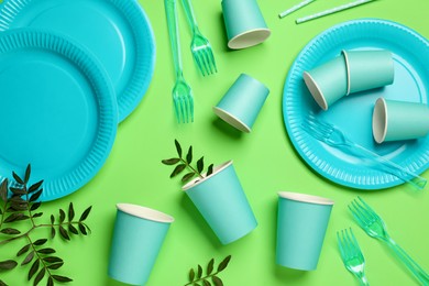 Flat lay composition with disposable tableware on green background