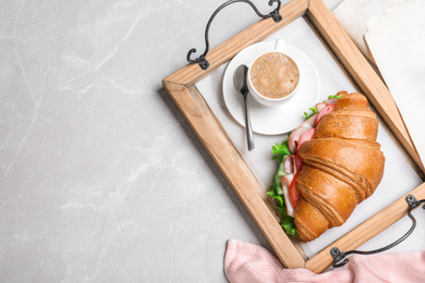 Tasty croissant sandwich and coffee on light grey marble table, flat lay. Space for text