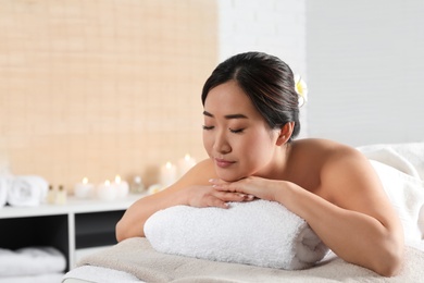 Beautiful Asian woman lying on massage table in spa salon. Space for text