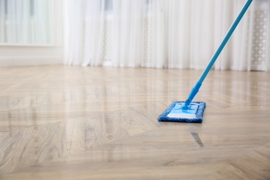 Washing of parquet floor with mop indoors, closeup. Space for text