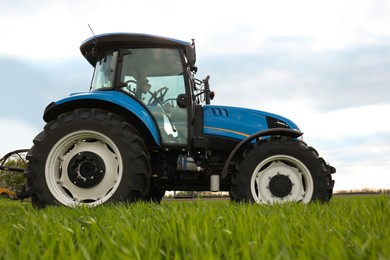 Modern tractor in field on sunny day. Agricultural industry