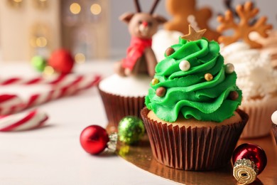 Tasty Christmas tree cupcake and baubles on white table. Space for text