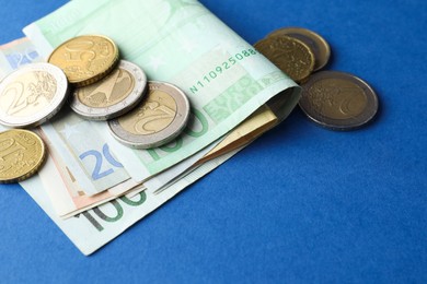 Euro banknotes and coins on blue background, closeup