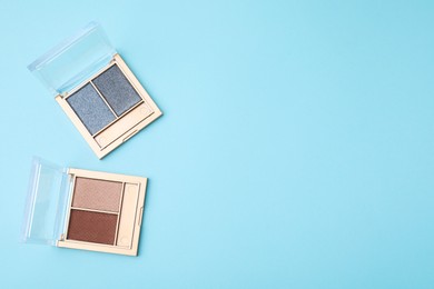 Photo of Beautiful eye shadow palettes on light blue background, flat lay. Space for text