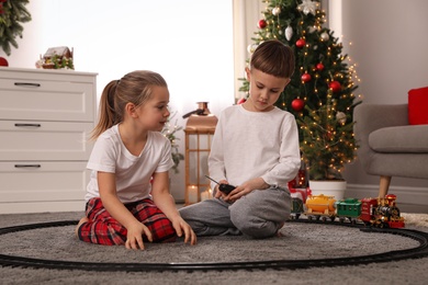 Children playing with colorful train toy in room decorated for Christmas