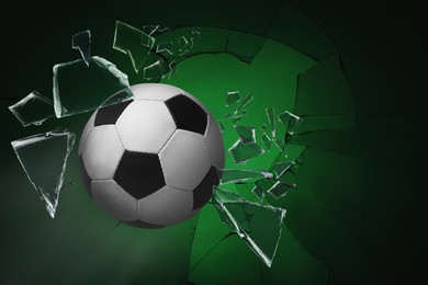 Soccer ball breaking up glass against green background