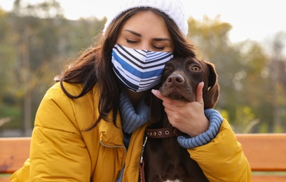 Woman in protective mask with German Shorthaired Pointer outdoors. Walking dog during COVID-19 pandemic