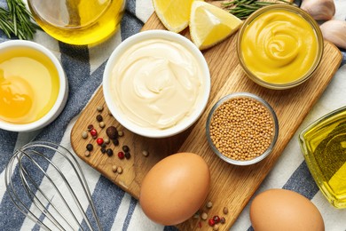 Photo of Bowl with fresh mayonnaise and ingredients on kitchen towel, flat lay