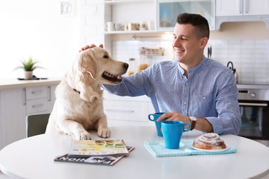 Photo of Portrait of owner with his friendly dog having breakfast at home