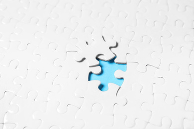 Blank white puzzle with separated piece on light blue background