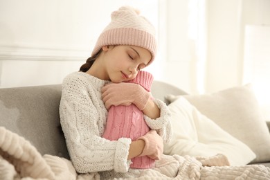 Photo of Ill girl with hot water bottle suffering from cold at home