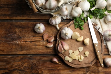 Flat lay composition with fresh sliced and whole garlic on wooden table, space for text. Organic product