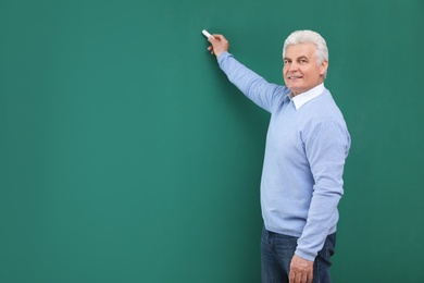 Portrait of senior teacher with chalk at green board, space for text